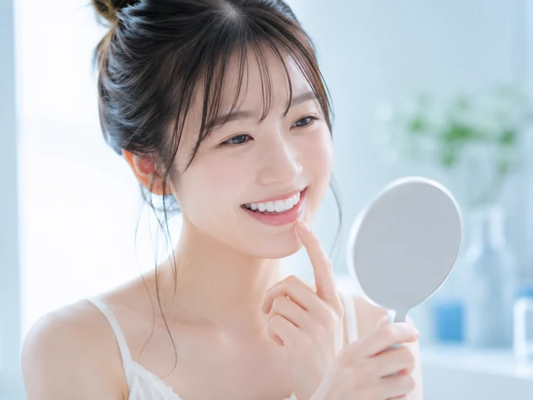 鏡を見ながら歯の白さを確認する女性